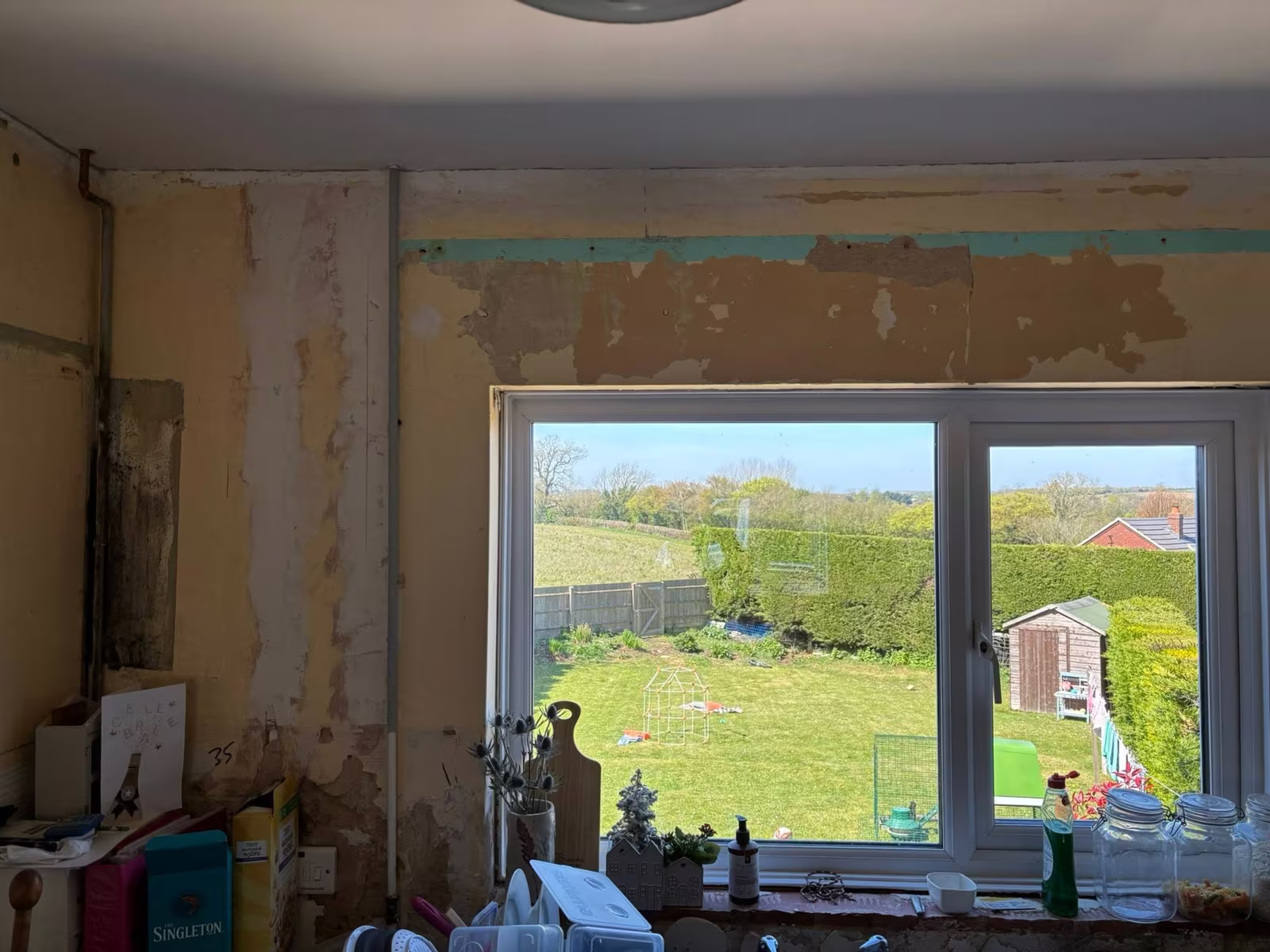 A kitchen before plastering, the old finish stripped back around the window over the sink