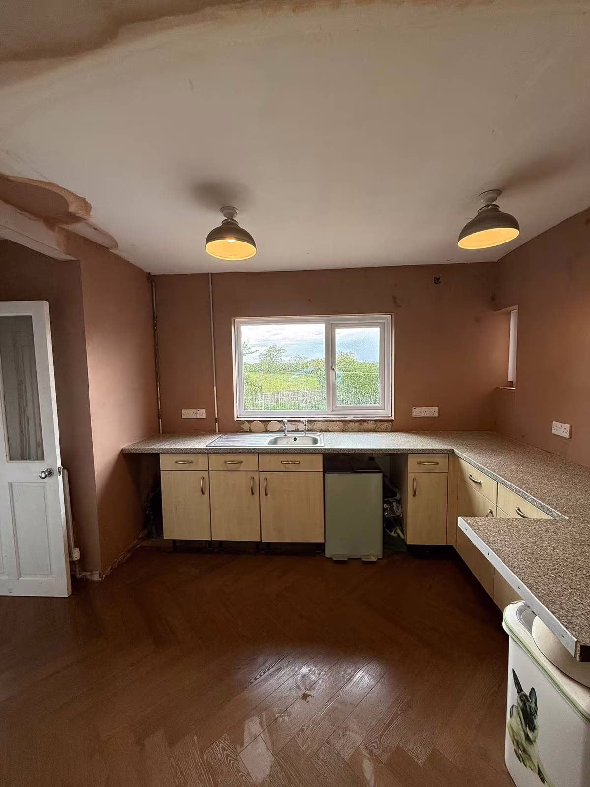 A kitchen with walls and ceiling freshly skimmed around the units, window looking over fields